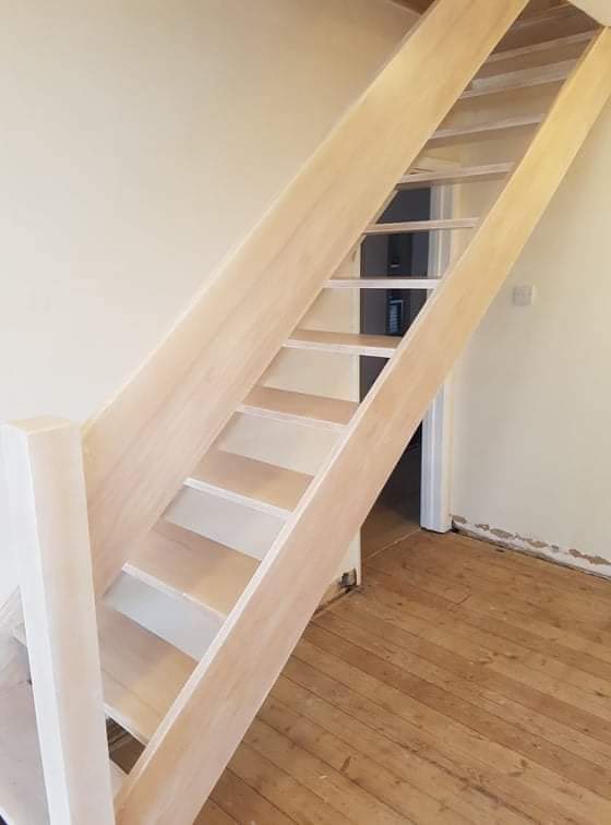Light wooden staircase with wooden panel handrail
