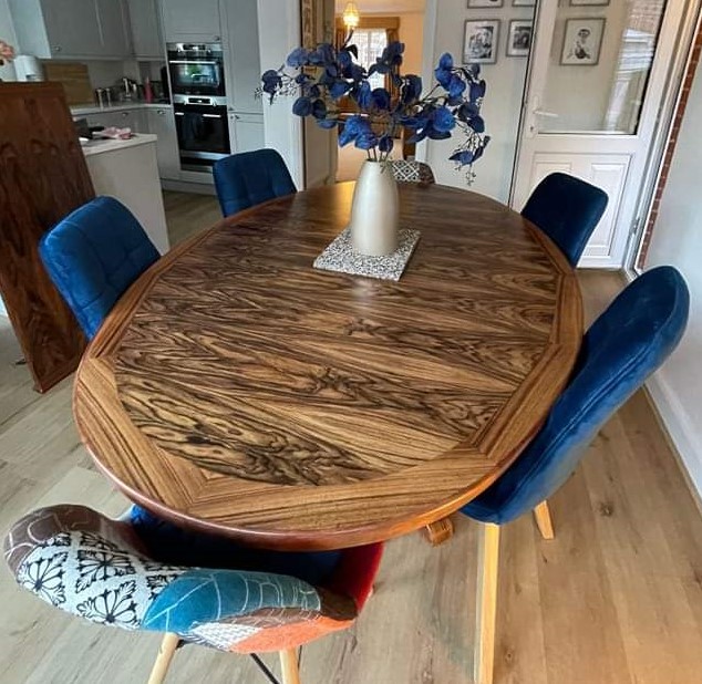 Rosewood oval dining table restored and polished with blue upholstered dining chairs in open plan dining lounge area